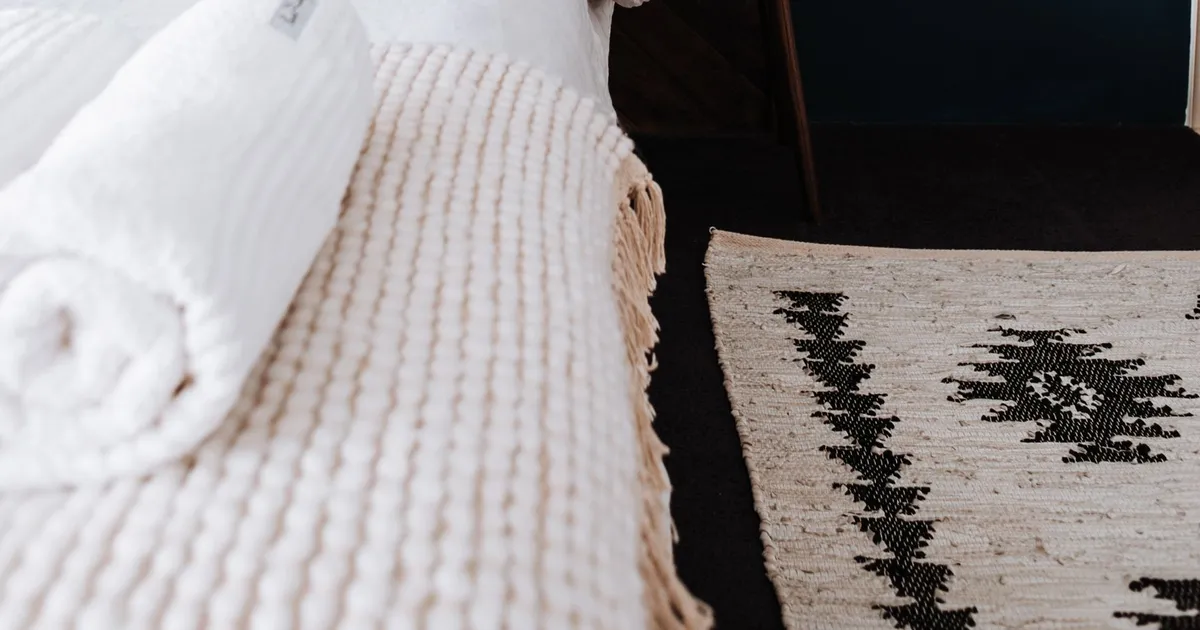 Wooden herringbone headboard and bedside table beside a bed with white bedding, an example of bedroom furniture from Vietnam